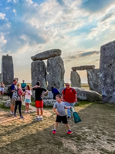 Group of tourists experiencing exclusive walk between the ancient stones at Stonehenge, with a scenic view of the countryside, on a guided tour from London