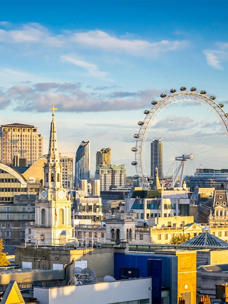 London Eye overlooking the Thames River with the city skyline on a cloudy day.