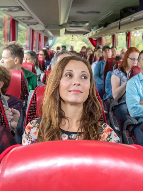 Tourists seated on an air-conditioned coach traveling to Windsor Castle, Bath, and Stonehenge.