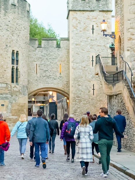 Tour group walking through Tower of London compound during after-hours ceremony.