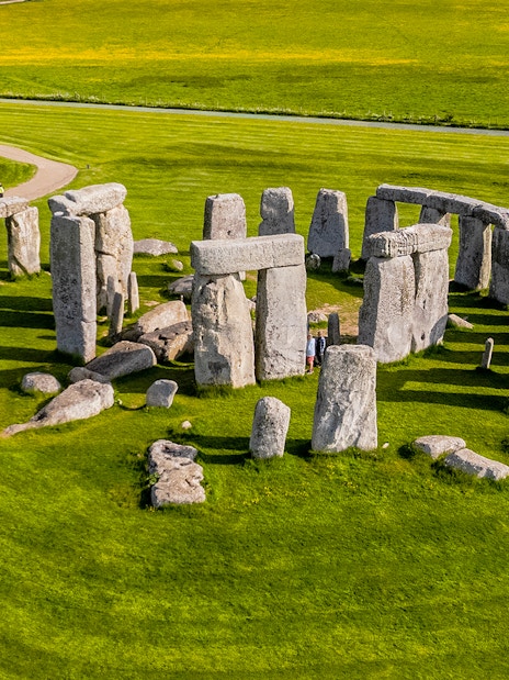 Tourists walking around Stonehenge on a guided day trip from London.