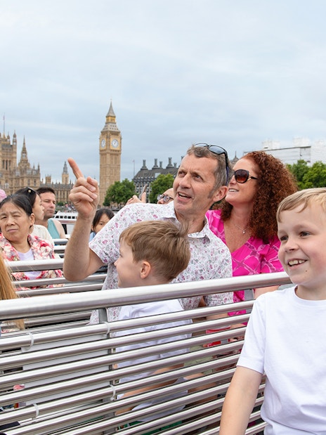 Family enjoying Thames River cruise with iconic London landmarks in the background.
