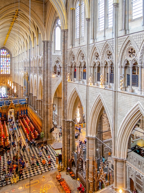 Nave of Westminster Abbey showcasing Gothic architecture with visitors exploring the historic interior.