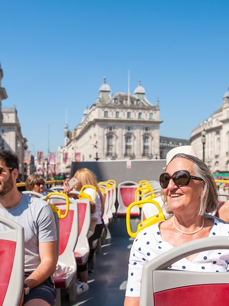 Tourists on a Hop-on Hop-off bus tour in London with views of Big Ben and River Thames cruise.