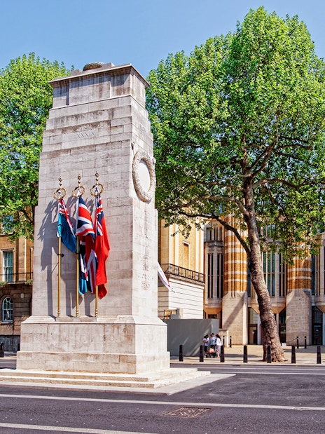 Cenotaph war memorial on Whitehall, London with surrounding flags and wreaths.