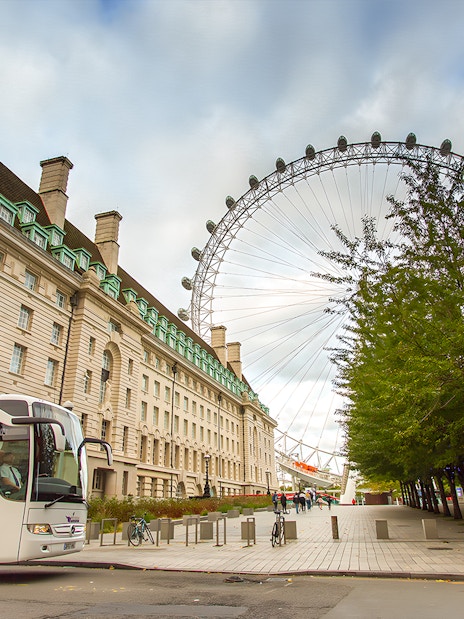 Double-decker bus on Magic of London Tour passing Big Ben, includes afternoon tea at Harrods.