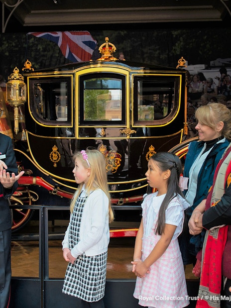 Warden guiding family visitors at The Royal Mews, Buckingham Palace, London.