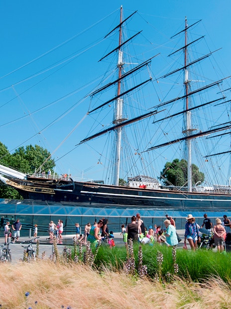 Cutty Sark ship docked at National Maritime Museum, London, with visitors exploring the historic vessel.