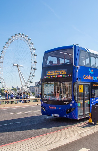 Hop on Hop off London bus passing by the London Eye on a sunny day.