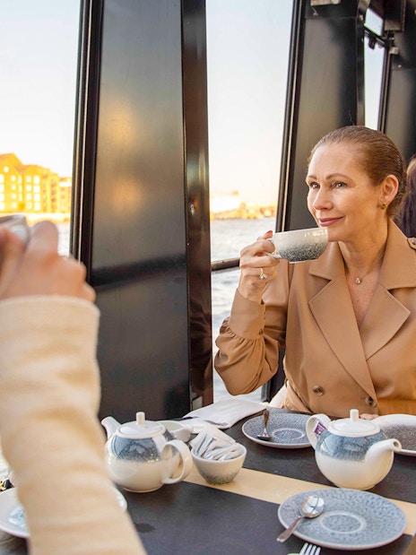 Thames River cruise boat passing under London Bridge with city skyline in the background.
