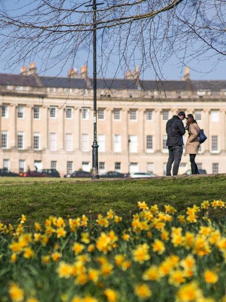 Tourists exploring Bath's historic streets, featuring Bridgerton filming locations and live music.