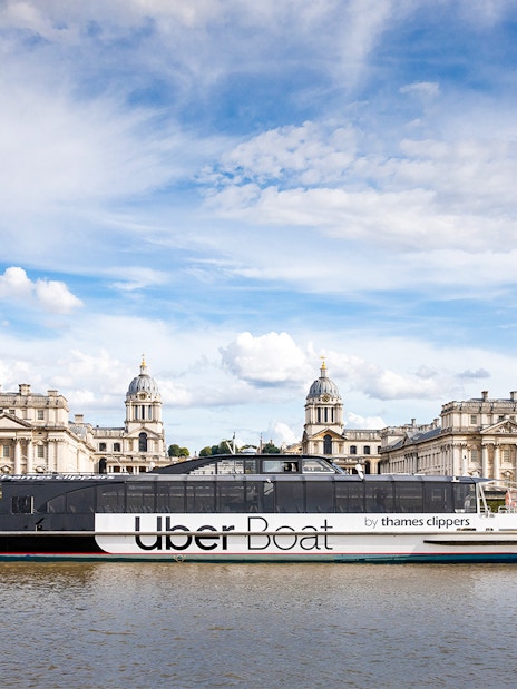 River cruise boat on the Thames with view of London's historic Greenwich buildings.